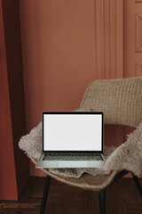 Wall Mural - laptop computer with blank screen on comfortable rattan chair against red color wall. aesthetic temp