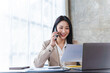 © Phushutter - Asian business woman have the joy of talking on the phone, laptop and tablet on the office desk.