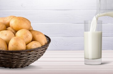 Wall Mural - Potato milk pouring into glass. Pouring vegan milk in glass, with potato on background. Home made potato milk made from boiled potatoes