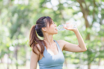  Athlete young beautiful woman drinking water from a plastic bottle at summer green park, Sport woman drinking water after work out exercising