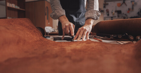 Wall Mural - Tailor cobbler hold different rolls natural brown leather, working with textile in workshop