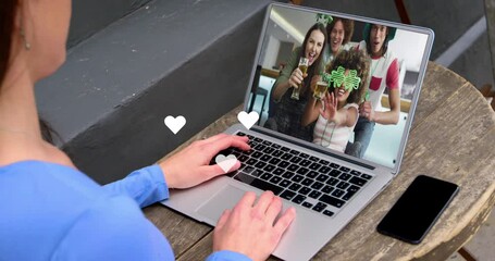 Sticker - White hearts floating over caucasian woman having a videocall on laptop at a cafe