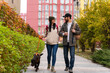 © NFstock - Caucasian couple in love walking along the street with brown Labrador breed dog with orange leash. Cloudy, warm autumn weather
