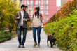 © NFstock - Full length view of the young stylish couple walking with dog in street. Man and woman happy together while looking at each other. Labrador breed, autumn season, casual style
