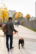 © NFstock - Back view of the man with backpack looking at his dog while walking with him through the street and enjoying a good sunny weather. Walking and taking care of the pet concept