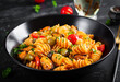 Classic italian pasta fusilli marinara with mussels, green olives and capers on dark table.  Fusilli pasta with sauce marinara