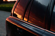 SUV on off-road rocky road. A beautiful red summer evening sunset is reflected in the SUV's tinted rear windows. Close-up.