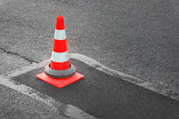 Patching of asphalt road. Striped orange and white reflective cone marks repair site