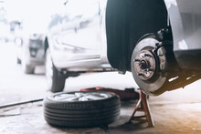 Repairing The Breaks Of A Car After A Street Crash. Details And Focus On Metal Parts And Worn Out Disc, Close Up Disc Brake Without Wheels Of The Vehicle For Repair.