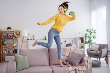 Wall Mural - Full length body size view of attractive cheerful girly girl dancing jumping on divan having fun listening pop song at home indoors