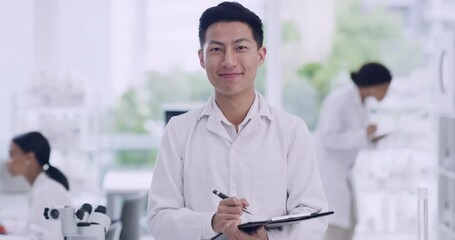 Poster - Happy biologist analyzing research report and writing on a checklist at a medical science laboratory. Portrait of a young male scientist with a clipboard on blur background in a lab with coworkers.
