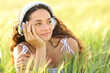 © Antonioguillem - Woman listening to music looking at side in a wheat field