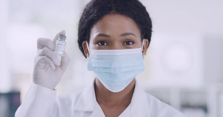 Aufkleber - A female doctor in a medical mask and rubber gloves holds a small ampoule containing the covid-19 vaccine in her hands. Young confident woman showing a small container while looking at the camera.