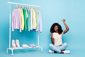 Poster - Full body photo of positive charming lady sit floor direct thumb fingers empty space isolated on blue color background