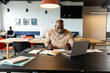 © WavebreakMediaMicro - African american mature businessman writing in diary while sitting with at laptop in creative office