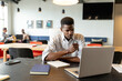 © WavebreakMediaMicro - Serious young african american businessman working on laptop in creative office