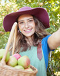 © Jade Maas/peopleimages.com - Cheerful farmer harvesting juicy organic fruit in season to eat. Portrait of a happy woman taking selfies while holding basket of fresh picked apples on sustainable orchard farm outside on sunny day