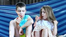 Two Adorable Kids Friends Eating Healthy Organic Food. Brother And Sister Eating Strawberry Sitting In The Blue Hammock In The Back Yard
