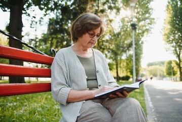 Poster - Retired woman reading a book on the bench