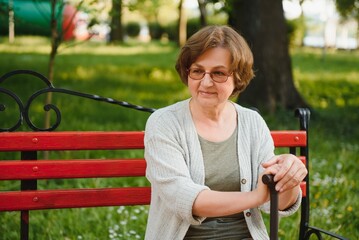 Poster - Senior woman with cane sitting on bench in park