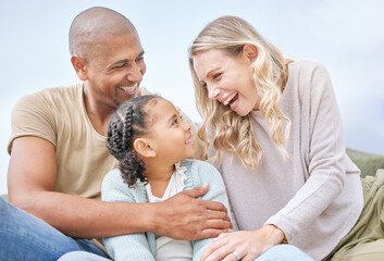 Canvas Print - Smiling married couple bonding with daughter on the beach. Adorable little girl embracing and laughing with her mother and father outside. Happy husband and wife enjoying free time with their child