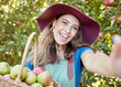 © Jade M/peopleimages.com - Portrait of one happy woman taking selfies while holding basket of fresh picked apples on sustainable orchard farm outside on sunny day. Cheerful farmer harvesting juicy organic seasonal fruit to eat