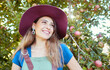 © Jade M/peopleimages.com - Trendy farm worker wearing a hat daydreaming on a fruit farm during harvest season. Young smiling farmer in front of a apple tree on a sunny day. The agricultural industry growing fresh produce