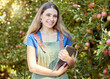 © Jade M/peopleimages.com - Portrait of a female farmer holding a digital tablet while standing by apple trees. Smiling woman using technology to prepare for harvest on her farm. Monitoring plant growth and agriculture