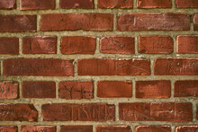 Closeup Of An Old Red Brick Wall With Carvings And Copyspace. Zoom In On Different Size, Shape And Patterns Of Bricks. Details Of Built Structure With Rough Surface, Sketched Or Scratched Markings