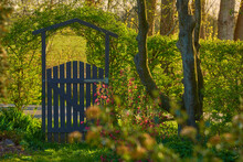 Small Wooden Gate In The Countryside. Lush Green Garden Upon Entrance To Private Home In The Woodlands. Sanctuary Or Safe Haven In Remote Area In Nature. Frontyard With Trees, Plants And Green Grass