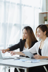 Wall Mural - Atmosphere in the office of a startup company, two female employees are discussing, brainstorming ideas to working on summaries and marketing plans to increase sales and prepare reports to managers.