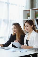 Wall Mural - Atmosphere in the office of a startup company, two female employees are discussing, brainstorming ideas to working on summaries and marketing plans to increase sales and prepare reports to managers.