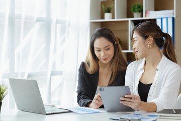 Wall Mural - Atmosphere in the office of a startup company, two female employees are discussing, brainstorming ideas to working on summaries and marketing plans to increase sales and prepare reports to managers.