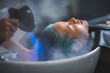 © chokniti - young beautiful woman client getting hair treatment in beauty salon with professional female stylist hairdresser, using shampoo and water on person head to clean and coiffure hair fashion service
