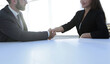 © ASDF - Business partners handshaking over business objects on workplace