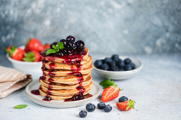 Wall Mural - Pancakes with berry fruit preserves topping over blue concrete background. Copy space for text or design elements. Sweet breakfast pancakes stack with jam