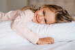 © Maria - Happy smiling child girl lying on the bed on white fluffy pillow good morning enjoy new day