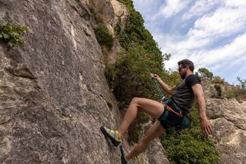 Young man rock wall climbing in Spain during summer time