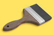 Paint bristle brush for repair work and construction on yellow background.