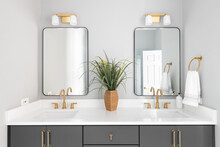 Bathroom A Grey Vanity, Gold Lights And Faucets, And White Marble Countertop.