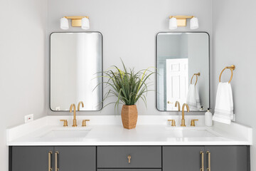 Bathroom a grey vanity, gold lights and faucets, and white marble countertop.