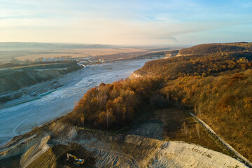 Aerial view of open pit mining site of limestone materials for construction industry with excavators and dump trucks