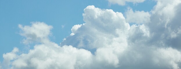 Wall Mural - Cloudscape. White ornamental clouds. Soft sunlight. Clear blue sky. Natural pattern, texture, background, wallpaper, graphic resources, design, copy space. Symbol of peace