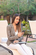 © Hugo - business girl using her smart phone in the courtyard of a hotel.