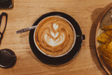 Vista superior de taza de café con leche, con dibujo artístico de flor en la espuma 