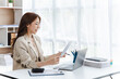 © makibestphoto - Business Asian woman using calculator and laptop for doing math finance on a wooden desk, tax, accounting, statistics, and analytical research concept.