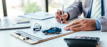 Man Signing Car Insurance Document Or Lease Paper. Writing Signature On Contract Or Agreement. Buying Or Selling New Or Used Vehicle. Car Keys On Table. Warranty Or Guarantee. Customer Or Salesman.