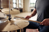 Fototapeta  - Close-up of man holding drumsticks and learning to play drums at drum kit at studio
