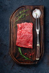 Wall Mural - Raw flank steak or Flat iron steak on a wooden board with grilling seasonings, top view