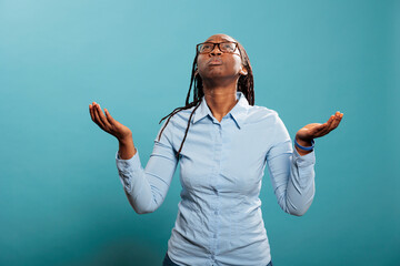 Wall Mural - Faithful african american woman with palms faced to sky pleading and begging to have her sins forgiven. Religious and spiritual young person praying for a better and forgiving world. Studio shot